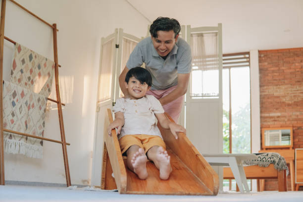 istock Joyful Asian father and son spending time together playing slide. 2158554631