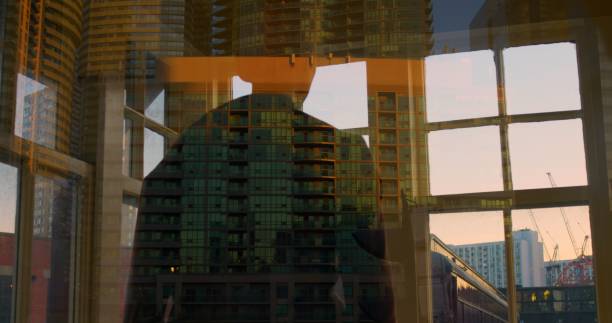 istock Reflective urban silhouette with sunset backdrop evokes contemplation. Cityscape reflection in window captures introspective, cinematic mood. Abstract blend of man, architecture emphasizes solitude. 2158554903