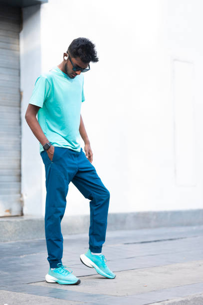 istock Young Man Checking Smartwatch While Standing in Casual Teal Outfit 2158555110