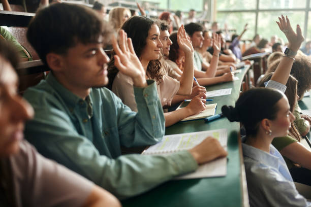 istock College students raising their hands on a class at lecture hall. 2158555351