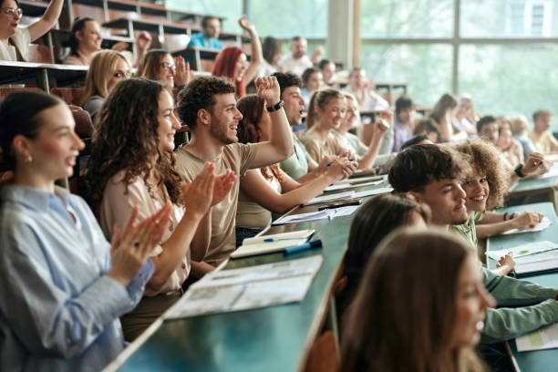 Cheerful college students applauding on a class at lecture hall.