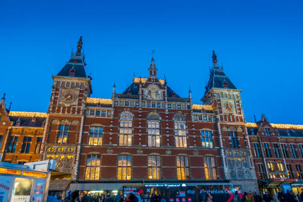 Amsterdam, Netherlands - Dec 1, 2019: Amsterdam Centraal Station viewed from street level in the evening. A major European hub for public transport and tourism.