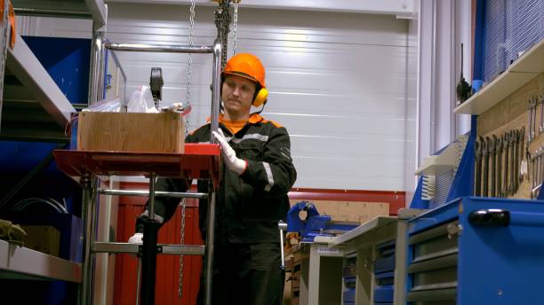 Worker in protective clothing sorting spare parts on factory workshop shelves. Emphasis on organization and safety demonstrates dedication to quality and precision in industrial setting