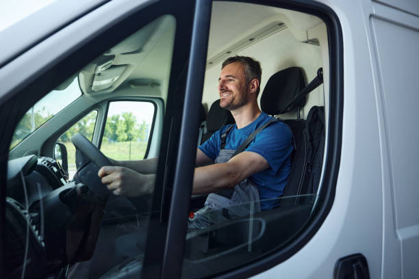Happy delivery man driving a van.