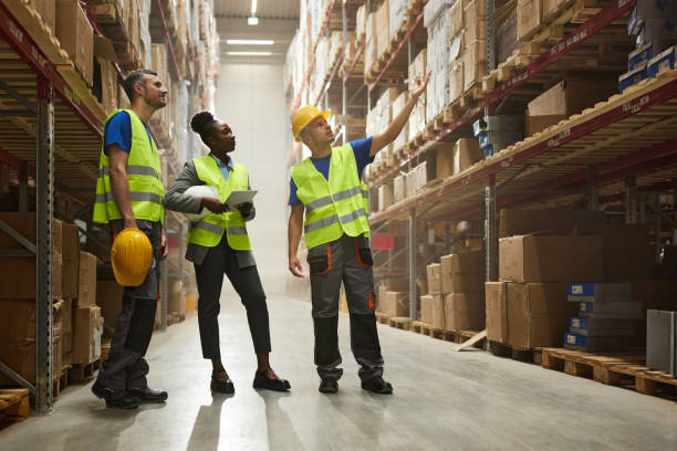 istock Manual workers planning shipping with female black inspector in storage room. 2158558749