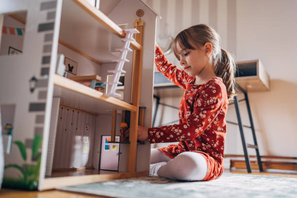 istock Imagination at Play: Young Girl Engages with a Dollhouse 2158559671