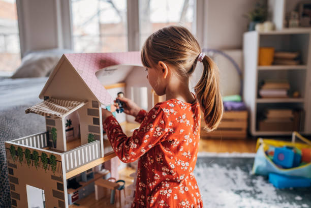 istock Imagination at Play: Young Girl Engages with a Dollhouse 2158560865
