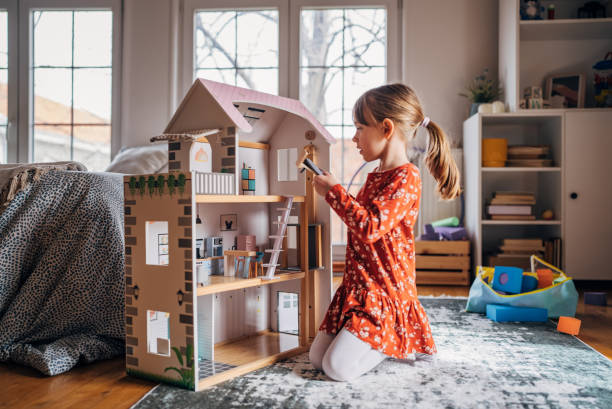 istock Imagination at Play: Young Girl Engages with a Dollhouse 2158561467