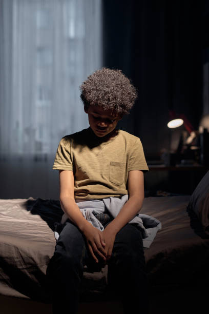 istock Teenage Boy Sitting on Bed in Dramatic Light 2158561509
