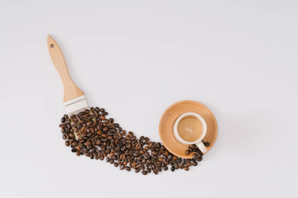istock Creative layout made with cup of coffee, roasted coffee beans and paintbrush on white background. Minimal coffee concept. Coffee art aesthetic idea. Flat lay composition. Top of view. 2158561736