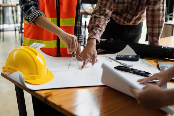 istock Architects Collaborating on Construction Project with Blueprints and Safety Gear in Modern Office Setting 2158562104