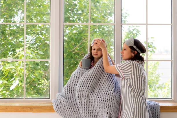 istock Mother caring for sick daughter at home near window. 2158564471