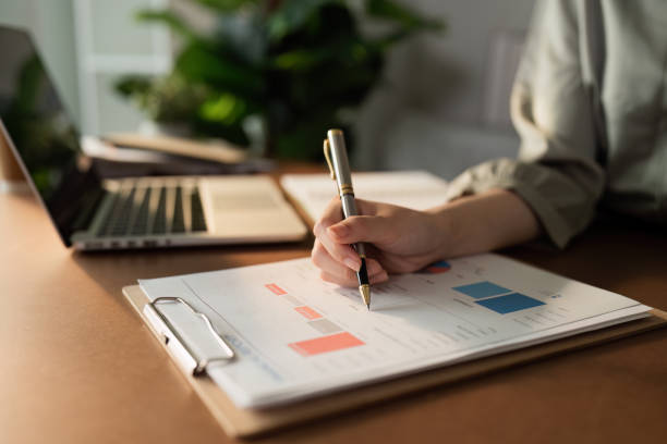 istock Business Professional Analyzing Financial Data on a Clipboard with Laptop in Background in Modern Office Setting 2158564590