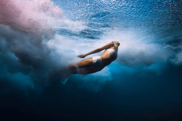 istock Surf girl dive underwater with ocean wave. Diving under barrel waves without surfboard 2158564715