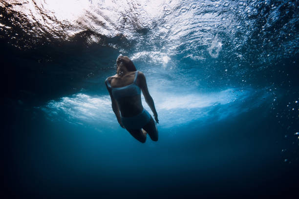 istock Woman swim underwater with crashing wave in ocean 2158564758
