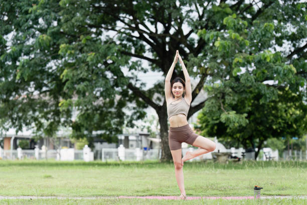 istock Young Woman Practicing Yoga Outdoors in a Park, Embracing Wellness and Mindfulness in a Natural Setting, Engaging in a Tree Pose for Balance and Inner Peace, Promoting a Healthy Lifestyle and Fitness 2158564888