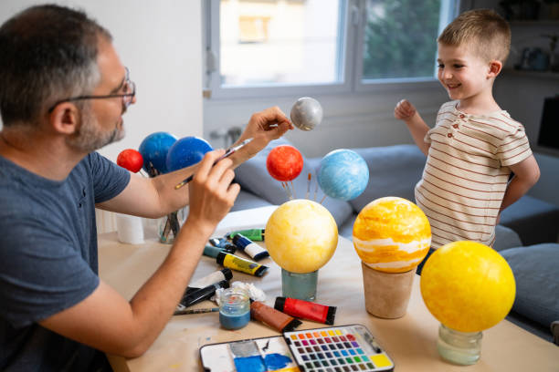 Dad and son painting a solar system model at home.