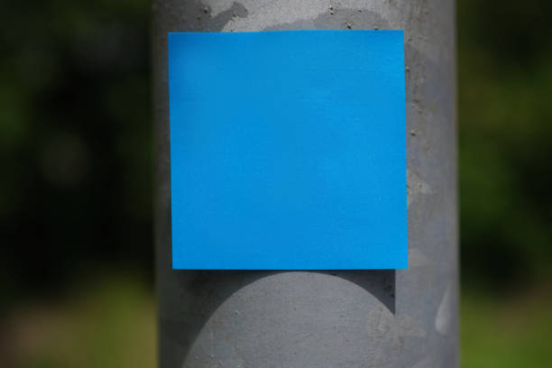 blank blue adhesive note stuck on a public sign pole.