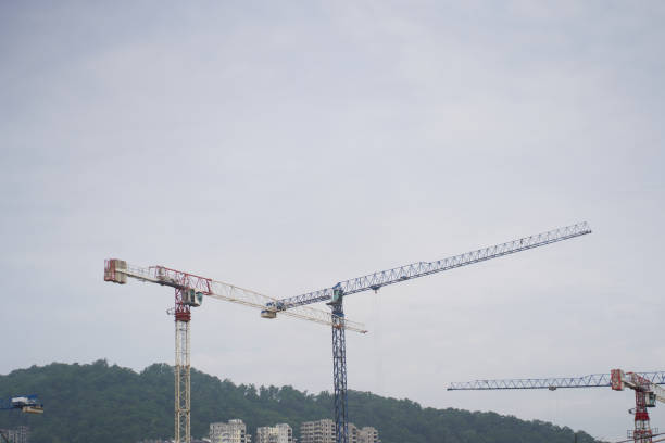 Several tall construction cranes against a clear blue sky.Construction crane and the upper part of the building with scaffolding on the background of the building under construction.High quality photo