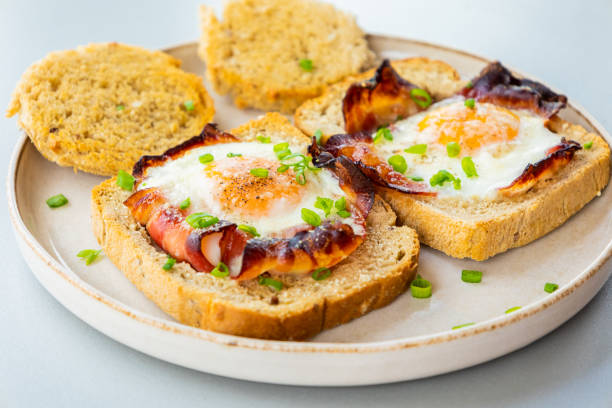 istock Baked Bacon and Eggs in Bread on White Plate with Fresh Green Onion Close-Up 2158570079