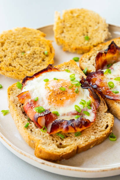 istock Baked Bacon and Eggs in Bread on White Plate with Fresh Green Onion Close-Up 2158570082