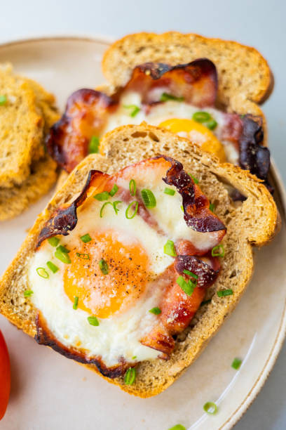istock Baked Bacon and Eggs in Bread on White Plate with Fresh Green Onion Close-Up 2158570086