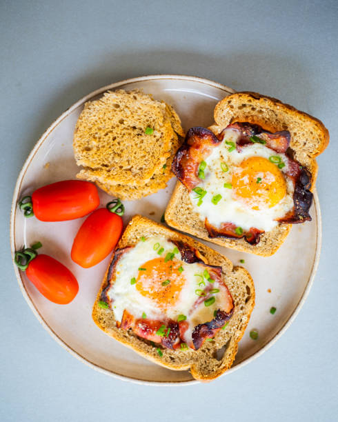 istock Baked Bacon and Eggs in Bread on White Plate with Fresh Green Onion Close-Up 2158570088