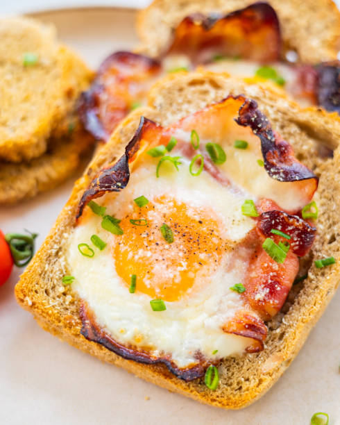 istock Baked Bacon and Eggs in Bread on White Plate with Fresh Green Onion Close-Up 2158570096