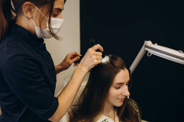 Doctor trichologist examines woman patient's hairs using trichoscope in clinic. Procedure of trichoscopy hair. Runs a trichoscope over scalp and looks result on monitor screen. Computer trichoscopy. el médico tricólogo examina el cabello de la paciente con un tricoscopio en la clínica. procedimiento de tricoscopia capilar. pasa un tricoscopio sobre el cuero cabelludo y mira el resultado en la pantalla del monitor. tricoscopia computarizada
