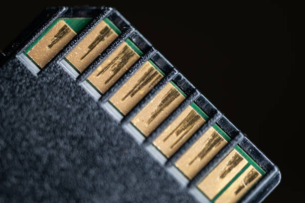 Close-up of the gold connectors on a black memory card against a dark background.