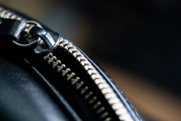 Close-up of a metallic zipper on a black leather surface.