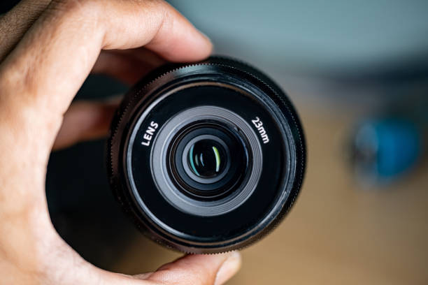 istock Close-up of a Mmes camera lens held by fingers 2158573531