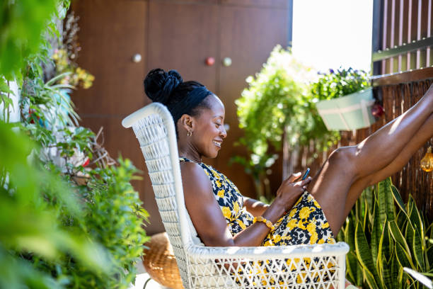 istock Beautiful woman using mobile phone while relaxing on the balcony at home 2158574134