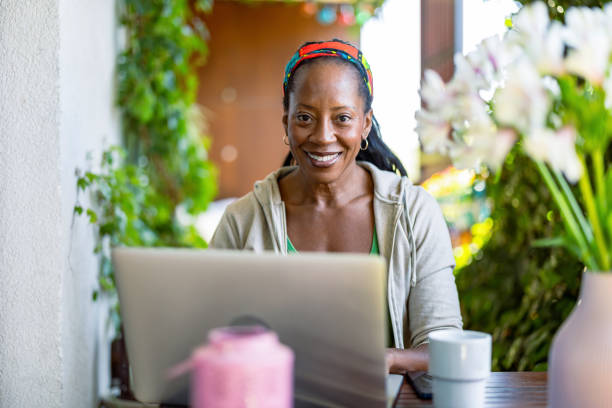 istock Portrait of smiling woman using laptop while sitting on the balcony 2158574149