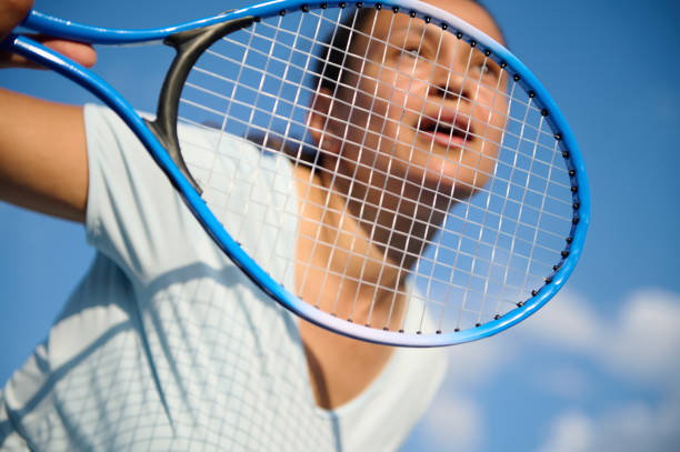 istock Woman playing tennis with focus on racket under blue sky 2158574201