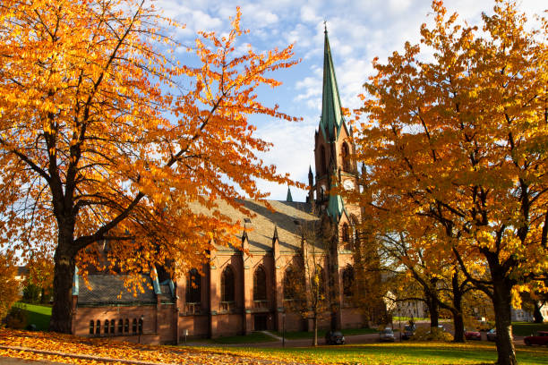 Church towers surrounded by yellow leaves. Colorful trees furring the fall time in autumn landscape in Drammen City Norway.