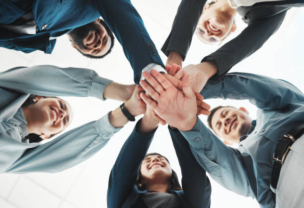 istock Business people, hands together and unity below for agreement, teamwork or collaboration at office. Low angle of group piling hand in team meeting, partnership or support and motivation at workplace 2158576899