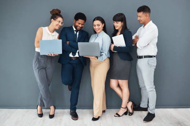 istock Business, teamwork and laptop on wall background for planning, strategy or online data management. Happy group of employees working on computer, diversity collaboration or research website technology 2158576957