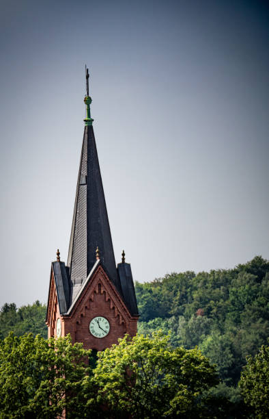 istock Tall Church Steeple With Clock and Trees in the Background 2158589973