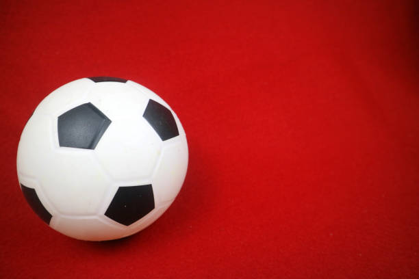 istock a small white and black toy rubber ball. Red background 2158590163