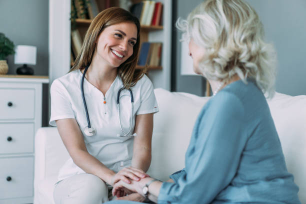 istock Happy doctor holding hands with senior patient for support at home. 2158593325