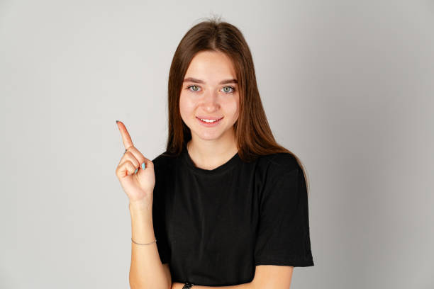 istock Smiling Young Woman Pointing to Copy Space Against a Grey Background 2158595386
