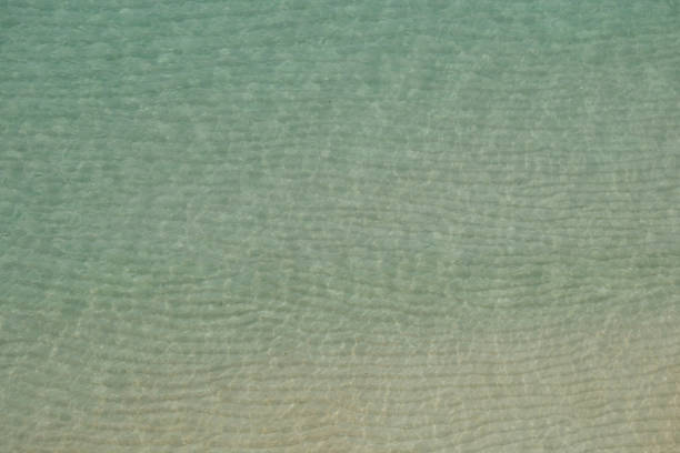 Views down from cliffs onto rippling shallow clear sea, near Porthcurno, South Cornwall.