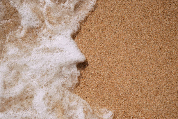 View of blue sea waves and white foam on a sand beach at Pattaya City Resort in Thailand.