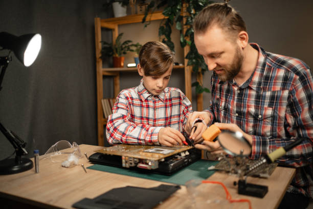 istock Father and son spend time together repairing a broken laptop, using a soldering iron and other repair tools. Family leisure 2158601920