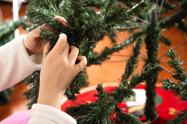 istock Girls' hands separating the twigs from the artificial Christmas tree 2158602359