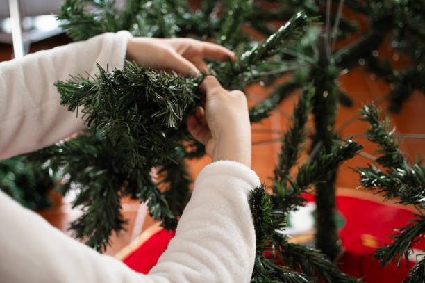 istock Some hands placing the artificial branches of the Christmas tree. 2158602375