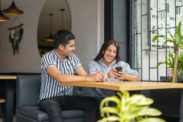 istock Couple talking and looking at cell phone in a restaurant. 2158603087