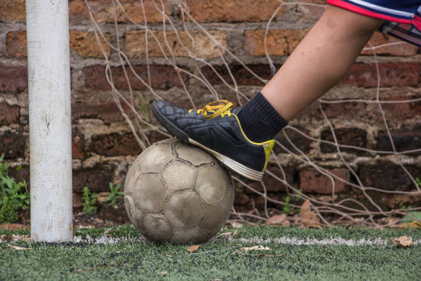 istock child's foot kicks an old soccer ball 2158608512