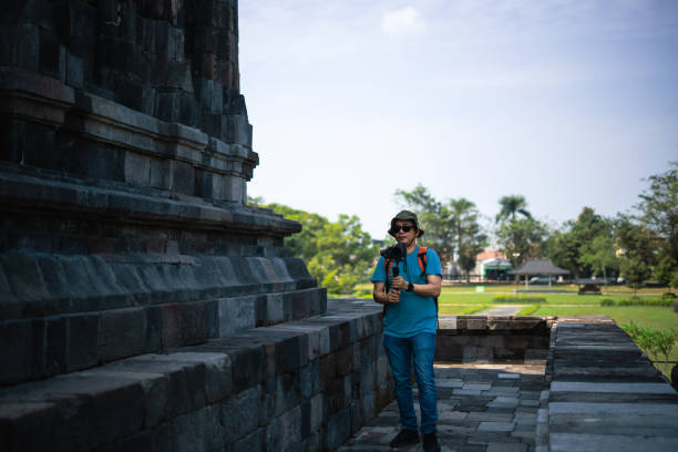 Man filming with camera and gimbal while standing while traveling in Prambanan temple, Indonesia